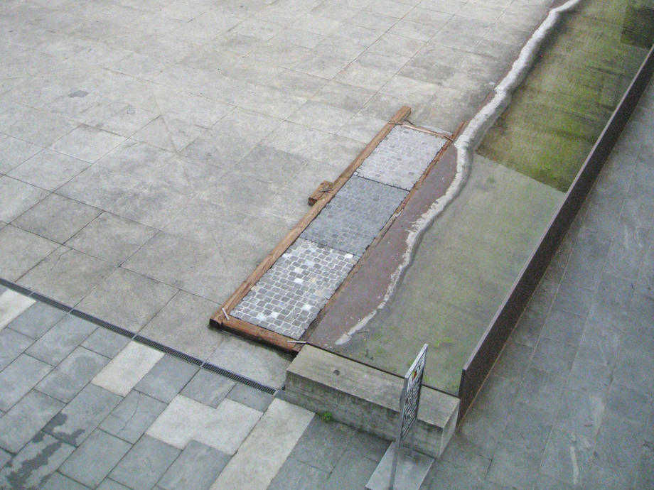 im Vordergrund maroder Plattenbelag und Brunnen ausser Betrieb
